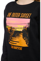 A person is wearing a hand-printed black Youth Outer Sunset Crewneck with a colorful design and the text, "The Outer Sunset, San Franpsycho," proudly showcasing the vibrant spirit of San Francisco.