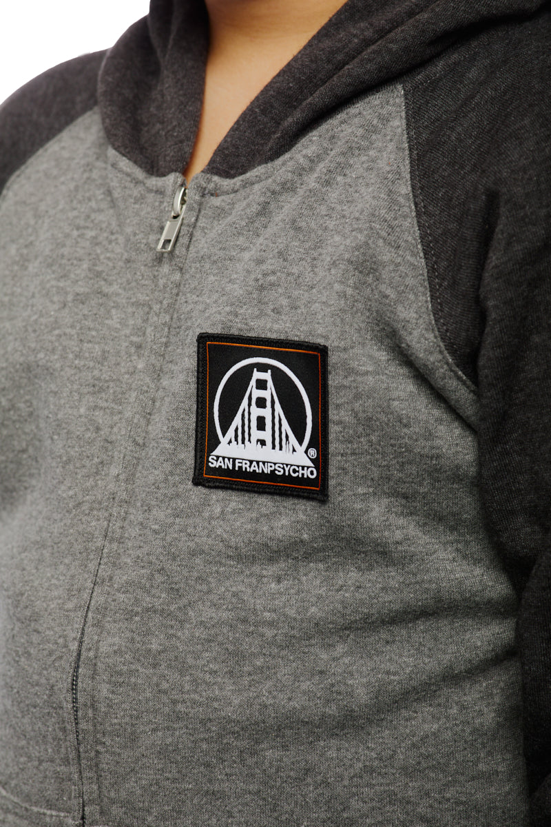 A child wears the Youth Two Tone Patch Hoodie, featuring a vibrant San Franpsycho patch with an iconic bridge design that captures the spirit of youthful adventure.