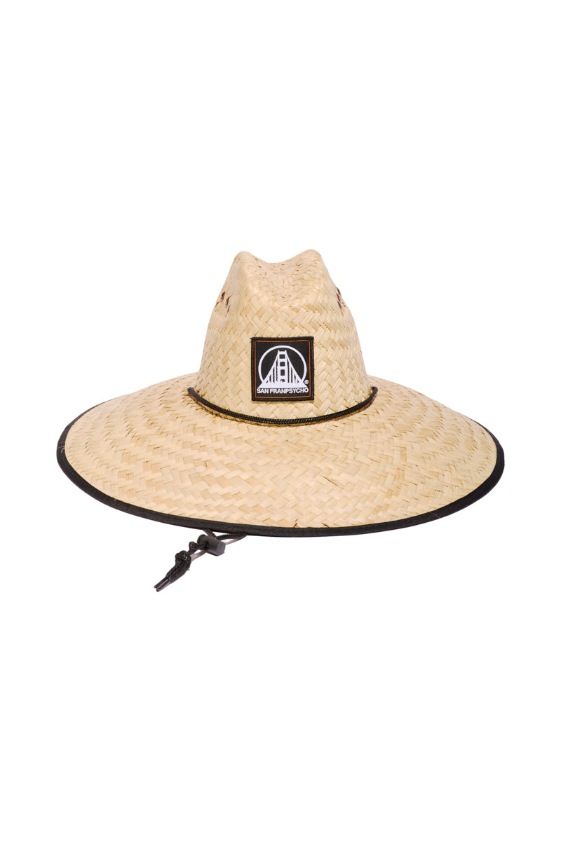 The Lifeguard Hat features a wide-brimmed woven straw design, black logo patch, and adjustable chin strap for excellent sun protection—ideal for classic beach or poolside style.