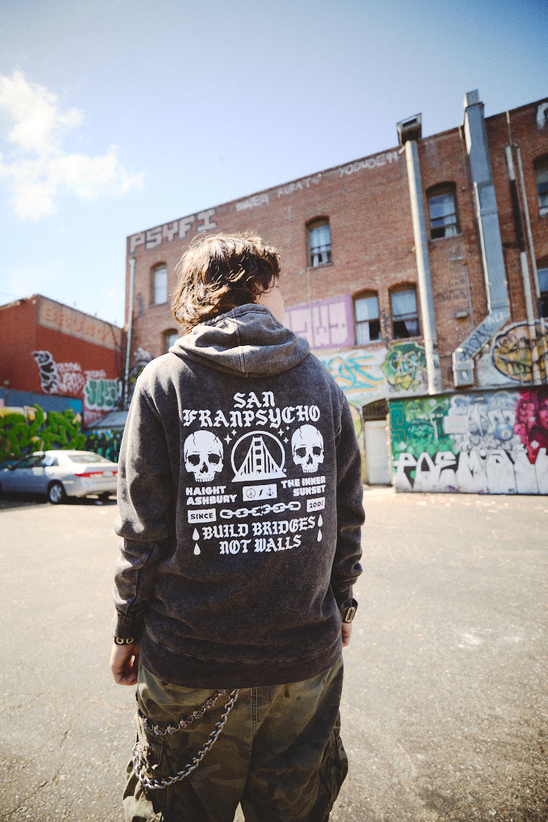 Amidst the vibrant, graffiti-adorned urban landscape, an individual in a BBNW Skull Pullover Hoodie epitomizes the spirit of Punk Rock 2023.