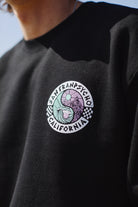Close-up of the Yin-Yang Crewneck in black, showcasing a colorful, 80s-inspired San Franpsycho California logo with checkerboard accents. This piece from the lively Spring 2024 collection effortlessly combines retro flair with modern charm.