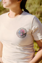 A person in a white Yin-Yang Tee boasting an 80s-inspired circular California-themed design stands outdoors, enjoying the comfort of Airlume cotton.