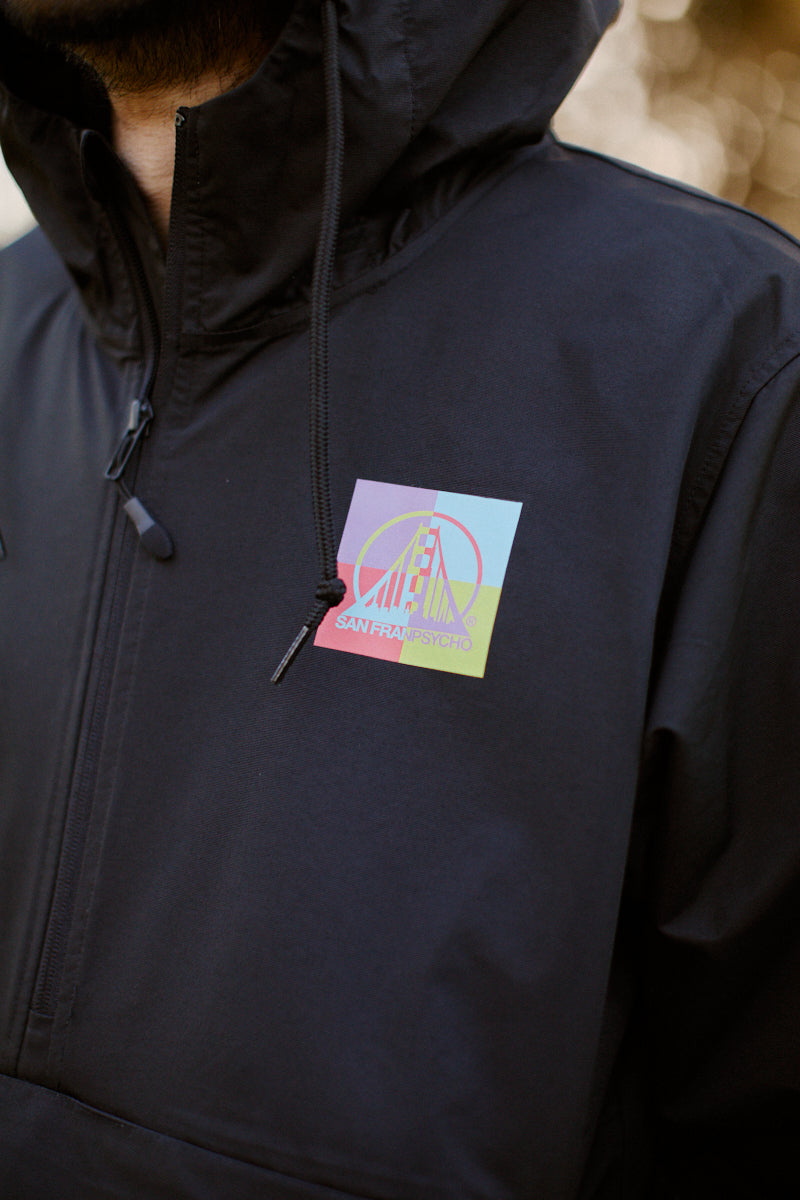 A person wearing a black hoodie featuring a vibrant San Francisco bridge design stands out against the backdrop. The graphic pairs perfectly with the Colorblock Windbreaker, adding dynamic flair and functionality to any outfit.