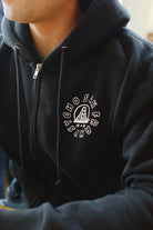 A person is seen wearing the ultra-soft Battle Cat Zip-Up Hoodie in black, featuring San Franpspycho with a bridge logo on the chest, enhanced by Ferris Plock artwork.