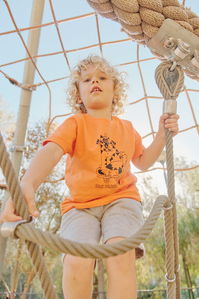 boy climbing ropes wearing Youth Kitty Poof orange Tee