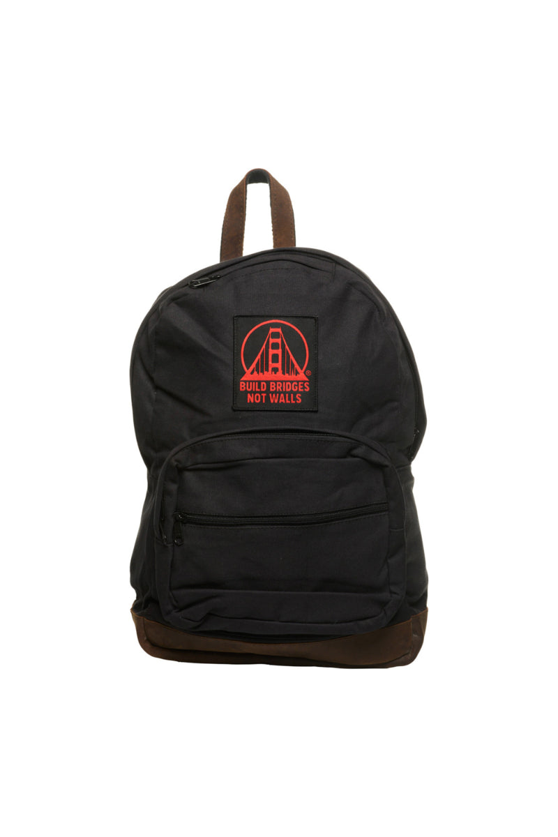 A black backpack with leather trims and a front pocket features a red patch that says Build Bridges Not Walls.