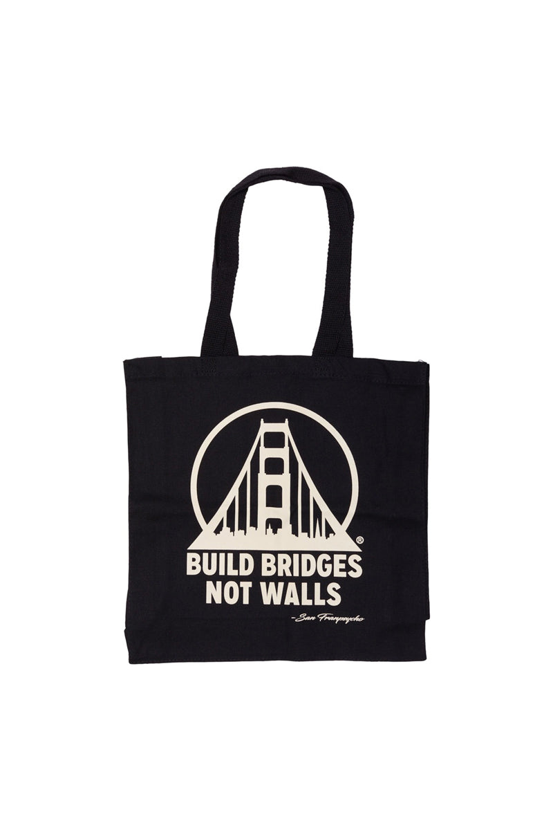 The Build Bridges Not Walls Tote is a hand-printed canvas bag featuring a striking bridge graphic and the inspiring message Build Bridges Not Walls.