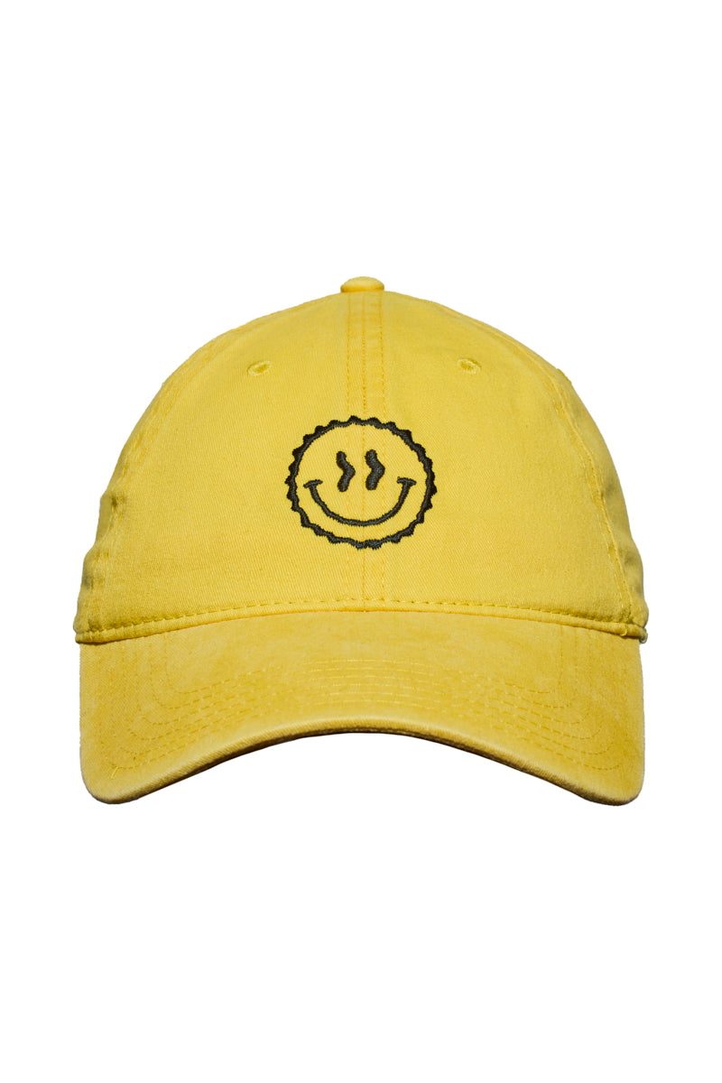 The Smiley Dad Hat is a yellow baseball cap featuring a black embroidered smiley face on the front and a classic fit for a timeless dad hat style.