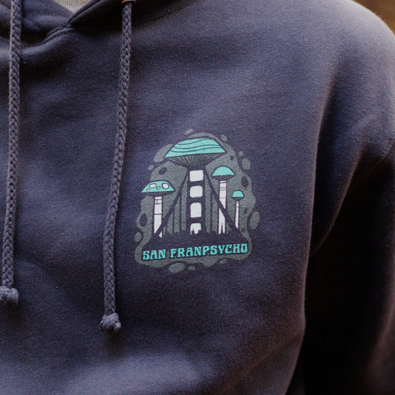 A person wearing the Mind Bloom Pullover Hoodie, which features a mushroom graphic logo.