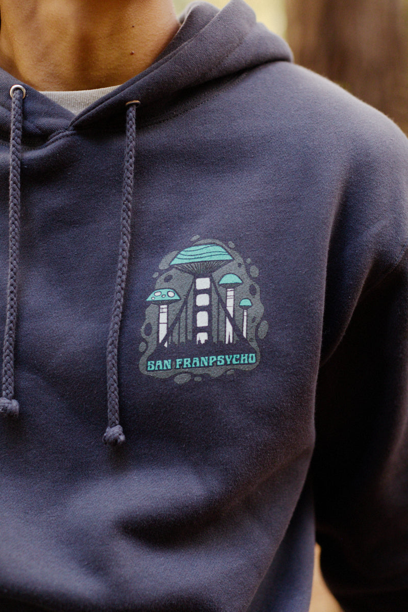 A person wearing the Mind Bloom Pullover Hoodie, which features a mushroom graphic logo.