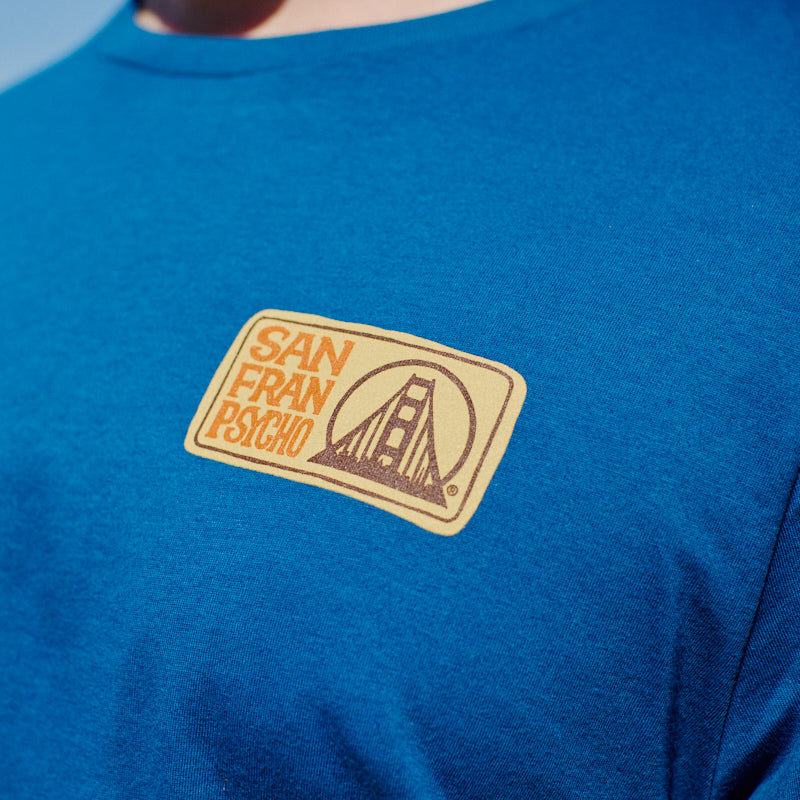Wearing the Elemental Tee - Blue, featuring a San Franpsycho patch and a Golden Gate Bridge graphic on the chest, captures the spirit of San Francisco.