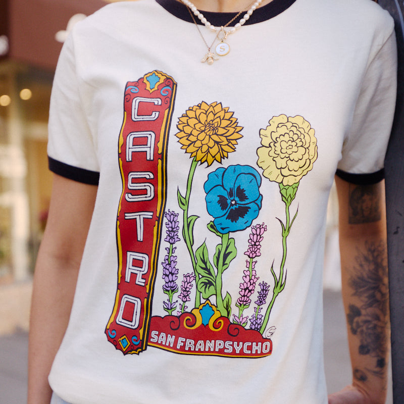 Wearing a Castro Pride Tee with colorful queer flowers outdoors—a vibrant nod to Pride design.