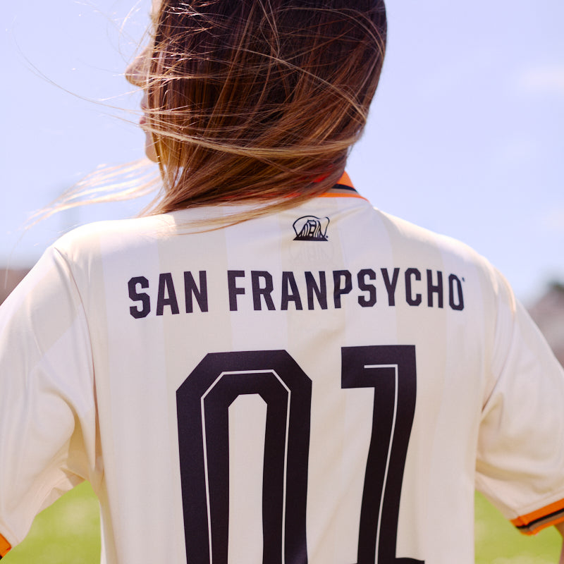 Person with long hair wearing the WC x SFP Jersey - Away, standing outdoors on a sunny day.