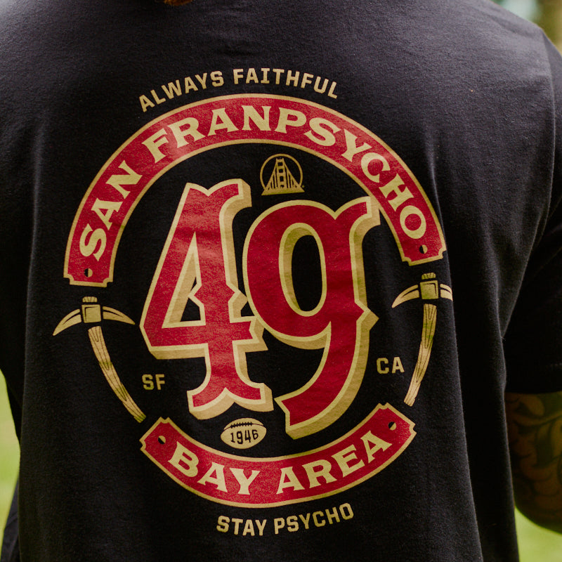 Wearing the Niners Faithful Tee, a black unisex t-shirt featuring San Franpsycho 49 Bay Area and graphic elements on the back—perfect for any fan representing San Francisco.