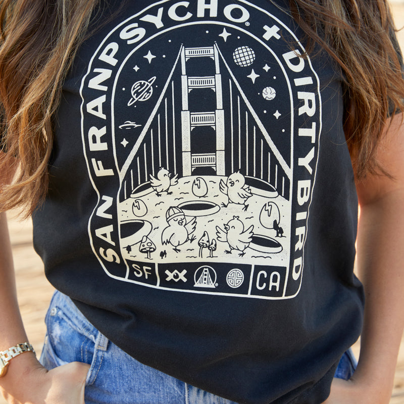 A woman wears the Moon Bridge Tee, a Dirtybird collaboration showcasing a San Francisco-inspired Golden Gate Bridge graphic.
