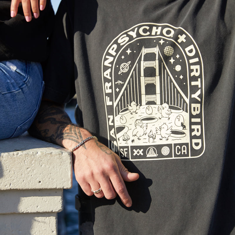 Man wearing the Moon Bridge Tee, a San Franpsycho + Dirtybird collab shirt with a Golden Gate Bridge graphic, showcasing classic San Francisco vibes.