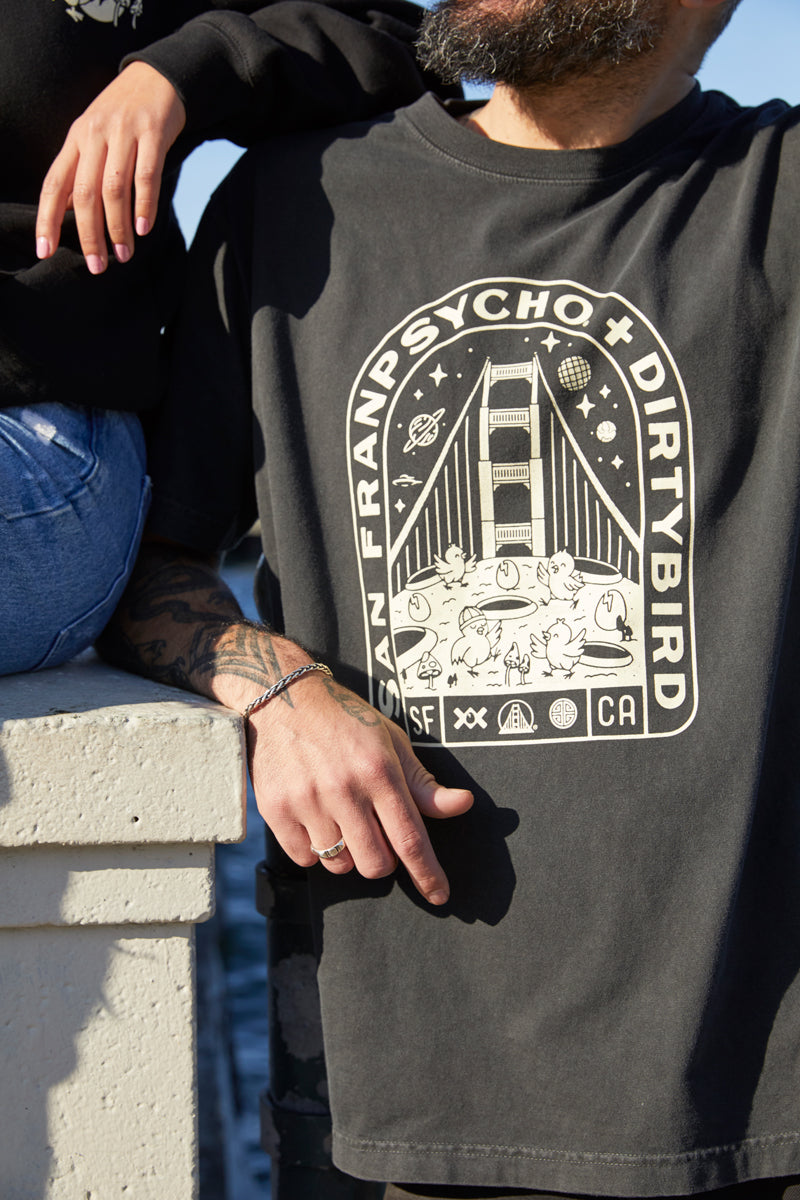 Man wearing the Moon Bridge Tee, a San Franpsycho + Dirtybird collab shirt with a Golden Gate Bridge graphic, showcasing classic San Francisco vibes.
