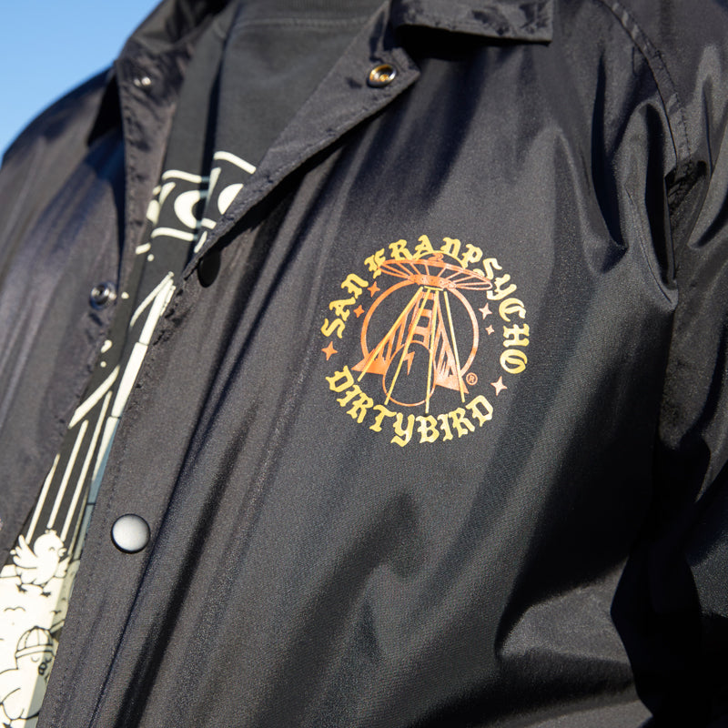 A person wears the Dirty UFO Coaches Jacket in black, showcasing a yellow San Francisco Dirtybird logo on the chest—a standout Bay Area streetwear piece.