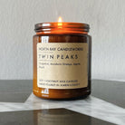 A candle from North Bay Candleworks, encased in a brown jar and labeled Twin Peaks, evokes the essence of the Bay Area with its invigorating blend of grapefruit, mandarin orange, agave, and peach scents.