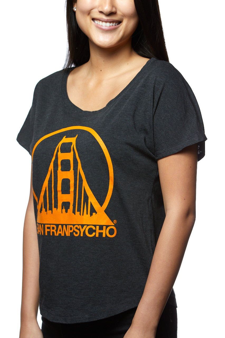 A smiling person wears the Charcoal & Orange Dolman featuring a dark San Franpsycho design with an orange graphic, hand printed in San Francisco.