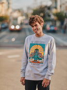 A person in an Inner Sunset Crewneck stands with a smile on a bustling street, as buildings and a bus blur in the background.