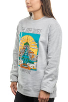 A woman wears the Inner Sunset Crewneck, a gray sweatshirt featuring a colorful city scene graphic and the text "The Inner Sunset San Franpsycho," embodying the lively spirit of San Francisco near Golden Gate Park.