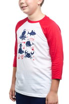 A child wears the Youth Ocean Club Baseball Tee, a 100% cotton shirt with a stylish white and red raglan design and vibrant blue sea creature graphics, perfect for any young member.