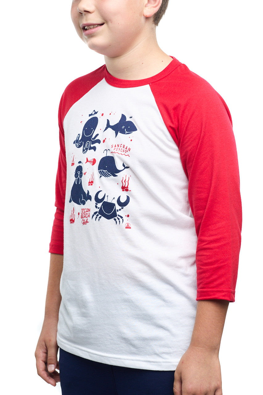 A child wears the Youth Ocean Club Baseball Tee, a 100% cotton shirt with a stylish white and red raglan design and vibrant blue sea creature graphics, perfect for any young member.