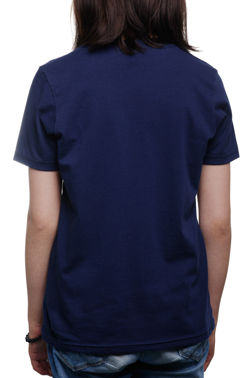 A person stands in their Youth Golden Gate Park Animals Navy Tee, facing away from the camera amidst the serene backdrop of Golden Gate Park.