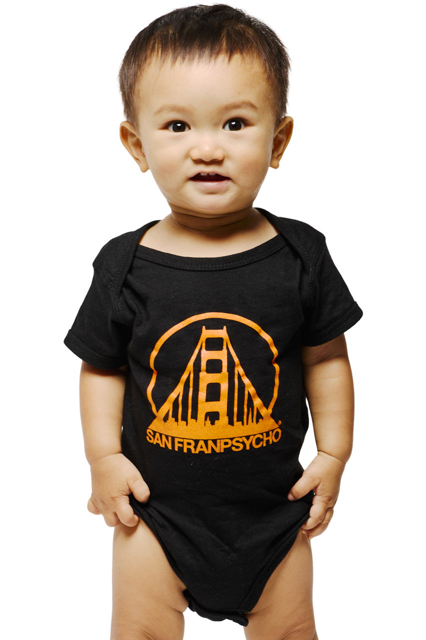 A baby wearing a Black & Orange Logo Onesie made of soft combed cotton, featuring an orange bridge logo and the words SAN FRANPSYCHO.