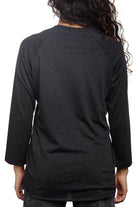 A person with long curly hair is seen from the back, wearing an everyday favorite—the Charcoal Raglan w/ Mini Logo.