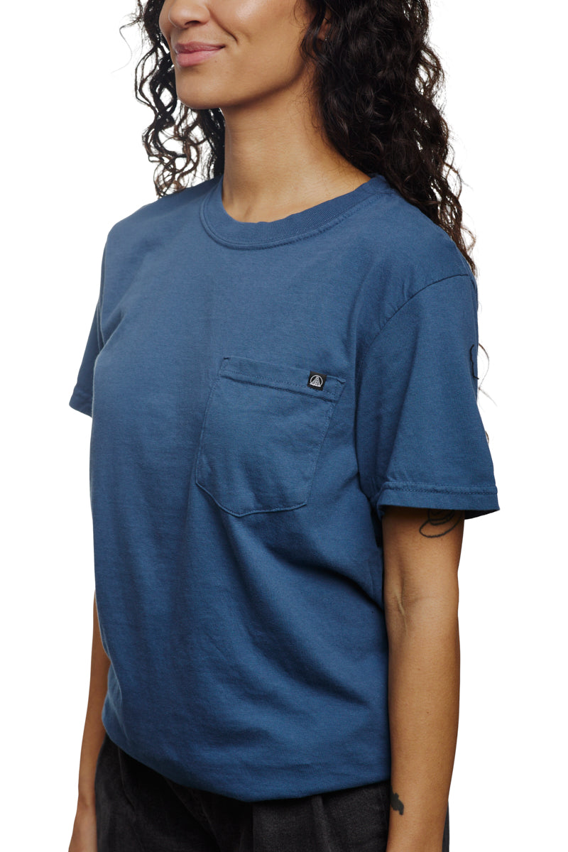 A woman wearing a Heavyweight Midnight Pocket Tee crafted from garment-dyed cotton smiles slightly.
