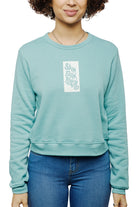A person wearing a teal Trippy Psycho Women's Crewneck, part of the Spring 2023 Collection, paired with blue jeans. This crewneck is made from a luxurious cotton/polyester blend and proudly displays "San Fran Psycho" across the front.