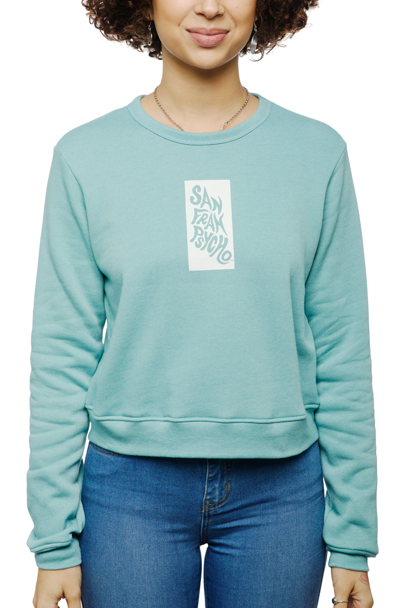 A person wearing a teal Trippy Psycho Women's Crewneck, part of the Spring 2023 Collection, paired with blue jeans. This crewneck is made from a luxurious cotton/polyester blend and proudly displays "San Fran Psycho" across the front.