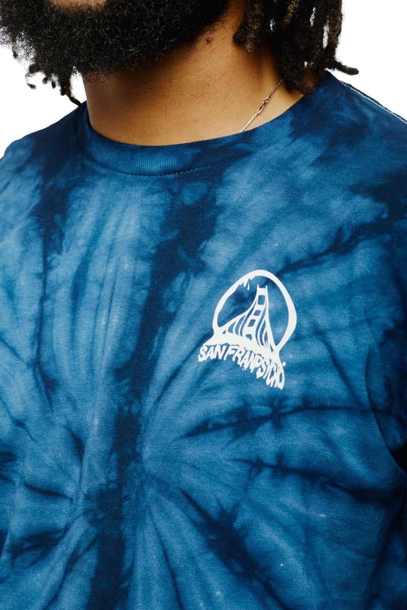 The individual wears a stunning navy long-sleeve shirt with a tie-dye pattern, highlighted by a bold acid logo of San Francisco's iconic bridge prominently displayed on the chest.
