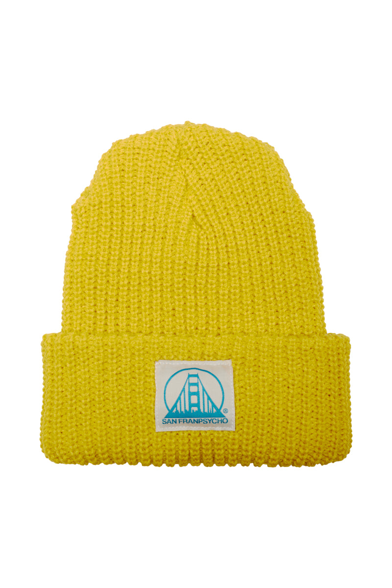 The Mustard Lumberjack Beanie features a folded brim and a natural/turquoise SFP logo patch, offering a cozy acrylic texture ideal for chilly adventures.