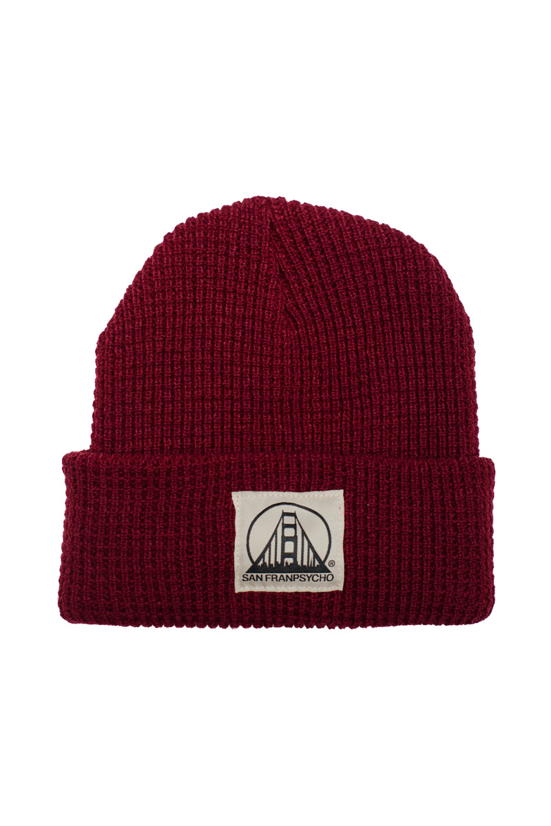 The Burgundy Waffle Beanie w/ Natural/Black SFP Logo features a soft acrylic build, a folded brim, and a white patch with a bridge graphic and bold text.
