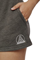 Close-up of a person wearing Women's Embroidered Logo Jogger Shorts made from a cotton/polyester blend, showcasing an embroidered Golden Gate Bridge logo, with their hand casually tucked in the pocket.
