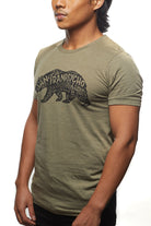 A man wearing the Cali Bear Tee, an olive green t-shirt with a graphic design featuring San Franpsycho, stands out, capturing the laid-back vibe of the Sunset District.