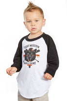A young child in a white and black Youth Take Meeeow Baseball Tee, featuring a playful cat graphic and "Take Meow to the Ball Game" text, is perfect for celebrating baseball season in San Francisco. Available in kids' sizes.