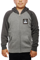 A child wearing the Youth Two Tone Patch Hoodie, featuring a bridge logo on the chest, stands against a white background, showcasing the perfect blend of style and comfort found in San Franpsycho's gray youth hoodies.