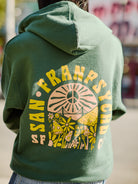 A person wearing the Hippie Hill Zip-Up Hoodie, featuring a SAN FRANPSYCHO and mushroom design on the back and made from 100% cotton, ideal for a stroll at Hippie Hill.