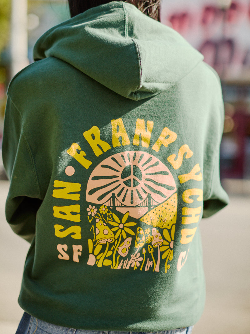 A person wearing the Hippie Hill Zip-Up Hoodie, featuring a SAN FRANPSYCHO and mushroom design on the back and made from 100% cotton, ideal for a stroll at Hippie Hill.