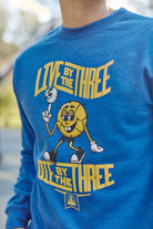 A person is wearing the Live by the Three Blue Crewneck, featuring a Warriors-themed design with a cartoon basketball and the text: "Live by the Three, Die by the Three.