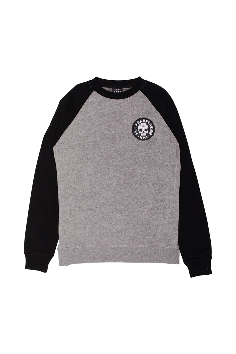 The BBNW Skull Patched Raglan Crewneck is a gray and black sweatshirt with a circular skull logo on the chest, ideal for achieving a punk rock look.