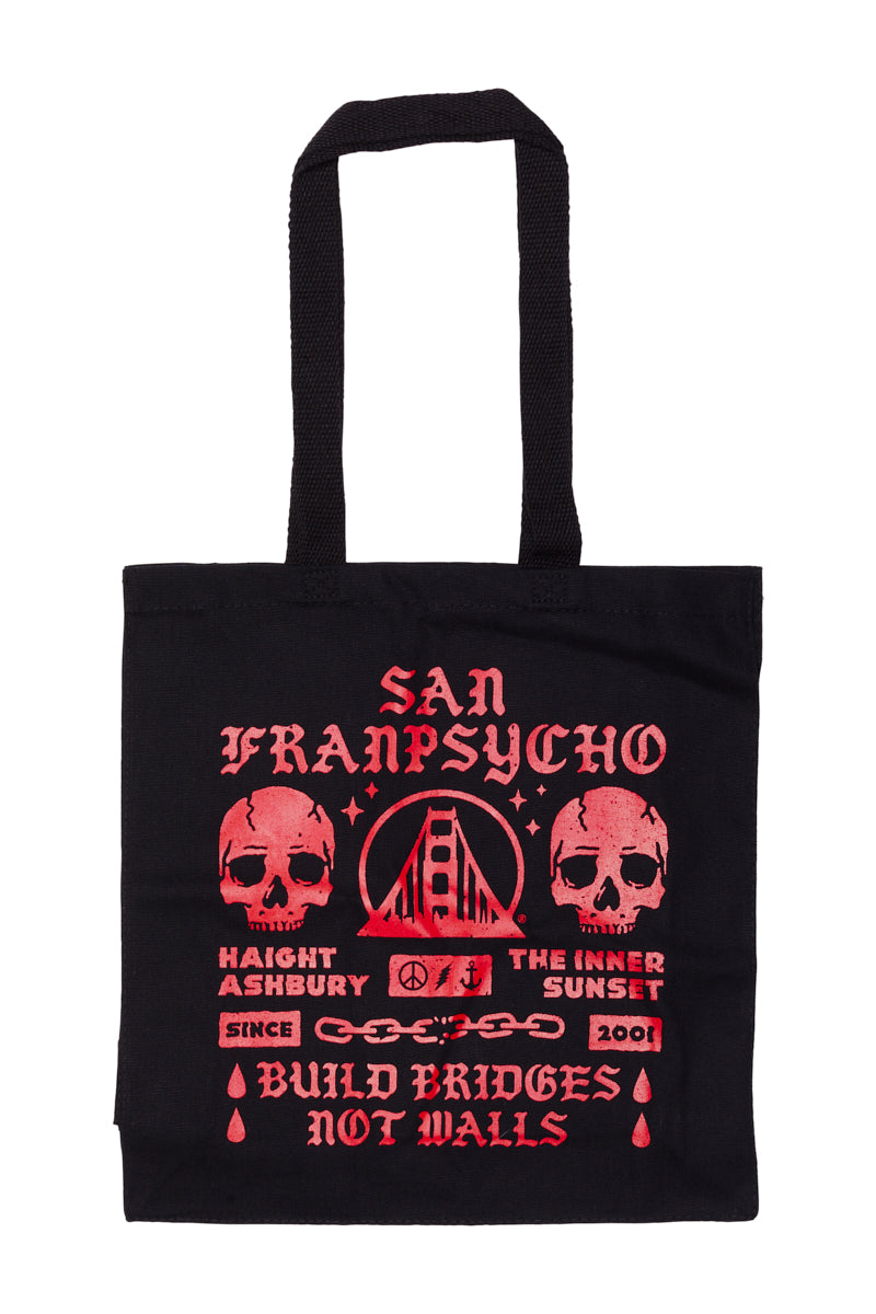 The BBNW Skull Tote is a hand-printed black canvas bag with bold red skulls, the Golden Gate Bridge, and "Build Bridges Not Walls," merging striking graphics with a powerful message.