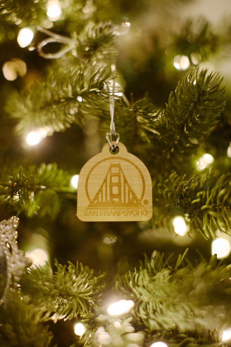 The SFP Wood Ornament, a laser-etched bamboo item resembling the Golden Gate Bridge, graces the Christmas tree with twinkling lights.