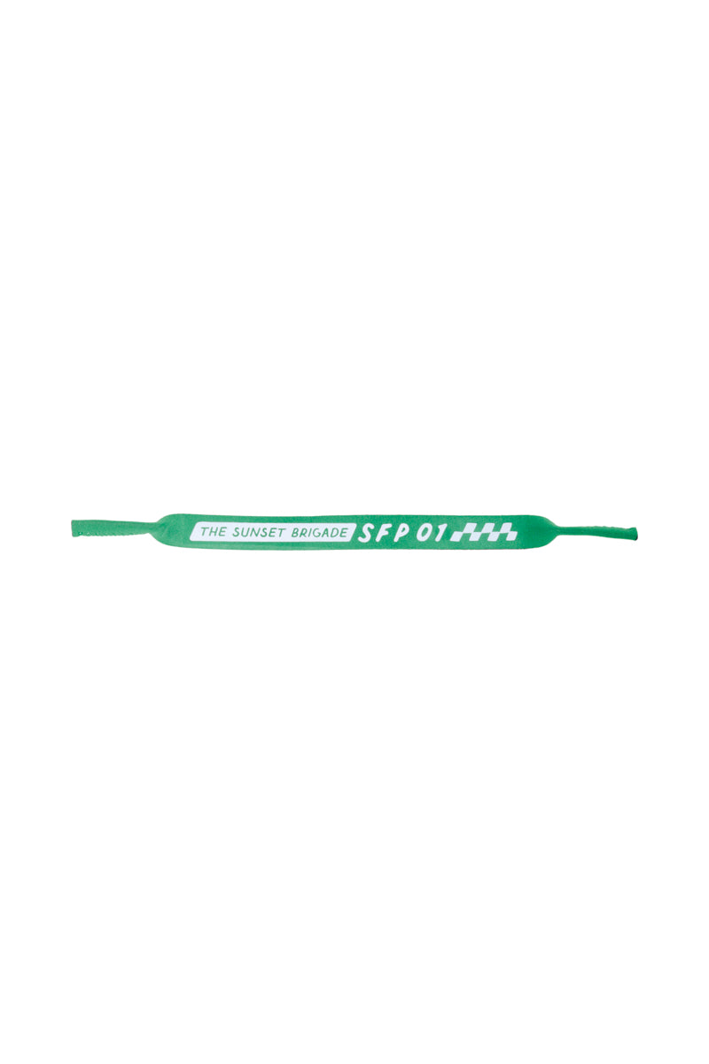 A green bracelet showcasing The Sunset Brigade SFO1 in bold white text, capturing the essence of an 80s-inspired collection. This accessory seamlessly pairs classic nostalgia with style, making it an ideal match for San Franpsycho Sunglasses Straps.