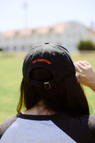 A person is wearing a Psychos Dad Hat from San Franpsycho, facing away, with the front of a building in the background.