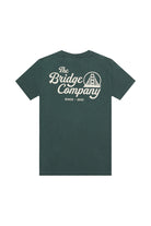 The Bridge Co Tee is a forest green heavyweight cotton shirt with "The Bridge Company," a bridge graphic, and "Since 2001" hand printed on the back.